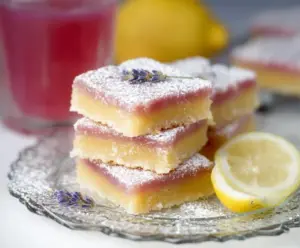 Delicious lavender lemon bars on a decorative plate with fresh lemon slices and lavender sprigs.
